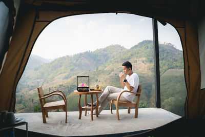 Young man sitting on seat in mountains