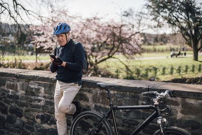 Senior man with cycling helmet using smartphone