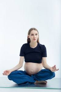 Portrait of young woman exercising against white background