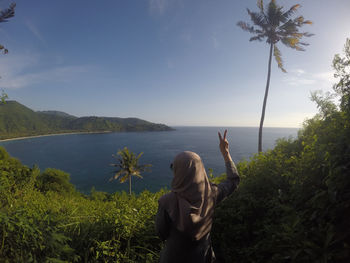 Rear view of woman in sea against sky