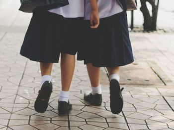 Low section of girls walking on street