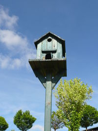 Low angle view of birdhouse against blue sky