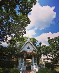 House amidst trees and building against sky