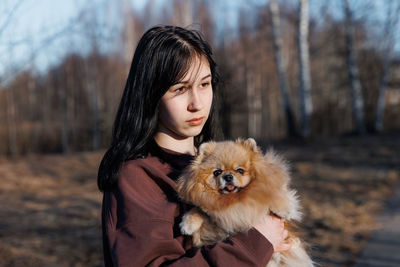 A girl walks with a dog in the park, outdoor recreation with a pet, a portrait with a small puppy