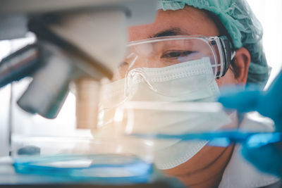 Close-up of doctor examining over microscope