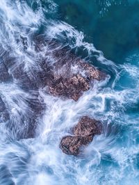 High angle view of sea splashing against rocks