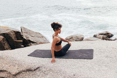 Rear view of woman sitting on rock