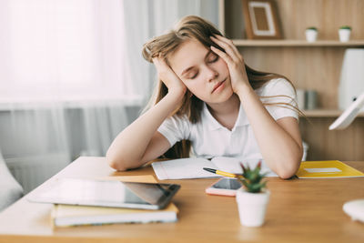 The exhausted schoolgirl is tired of doing homework, from studying at home, preparing for exams