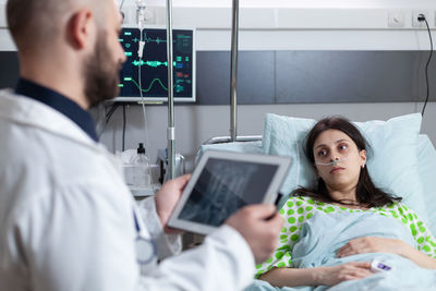 Young woman using digital tablet while sitting on bed at home