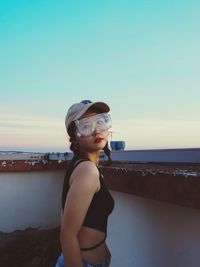 Portrait of young woman standing against sky 