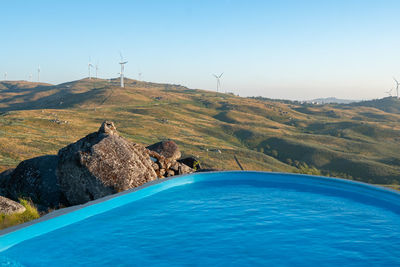 Beautiful pool with mountain landscape view with wind turbine eolic renewable energy