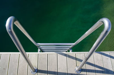 Close-up of ladder leading towards green water