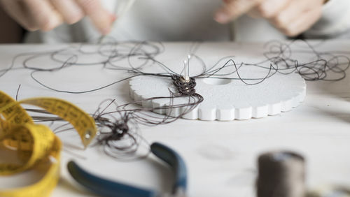 Cropped hands of woman working with thread on table