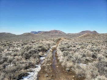 Scenic view of arid landscape against clear blue sky