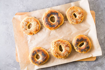 Baked bagels with poppy seeds and sesame seeds on parchment on the table. homemade pastries