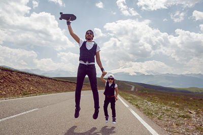 Father and son jump with black skateboard on the road against of mount everest in the summer