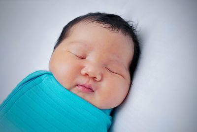 Close-up of baby sleeping on bed at home