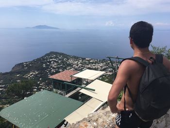 Rear view of man standing by sea against sky