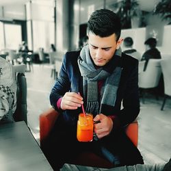 Young man drinking drink sitting in restaurant