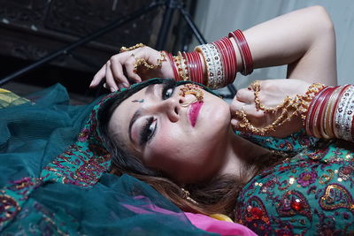 Portrait of beautiful woman wearing traditional clothing and jewelries while lying at home