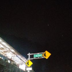 Low angle view of road sign against sky at night