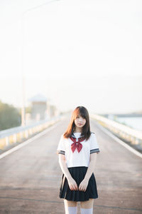 Portrait of young woman standing against sky