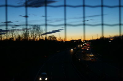 Cars on road in city against sky during sunset