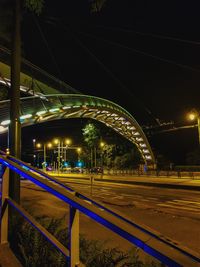 Light trails on bridge in city against sky at night