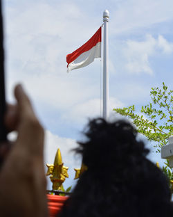 Low angle view of flag on cross against sky