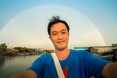 Portrait of mid adult man against rainbow sky