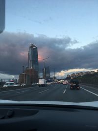 Cars on road against cloudy sky