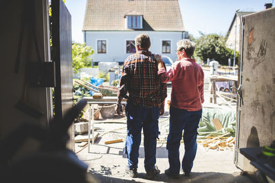 Rear view of senior couple looking at yard while standing in workshop