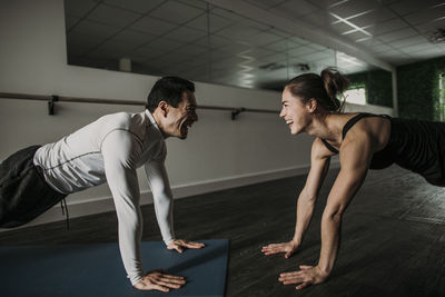 Fit male and female friends smile and do pushups together in a gym