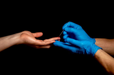 Midsection of people holding glass against black background