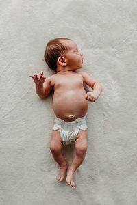 Newborn baby in only a diaper laying on white blanket