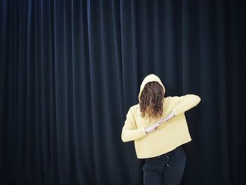 Woman in hood standing against wall