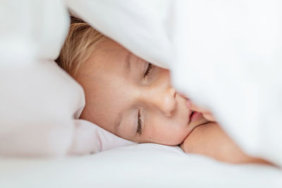 Close-up of cute girl sleeping on bed