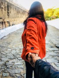 Cropped image of boyfriend holding girlfriend hand on footpath