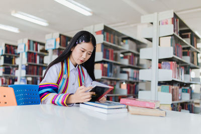 Woman reading book while sitting in library