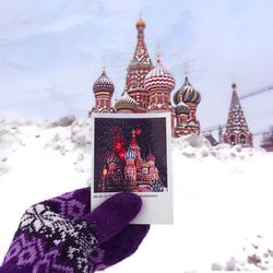 Cropped image of hand holding photograph against saint basil cathedral during winter