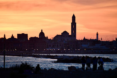 Silhouette of buildings against cloudy sky during sunset