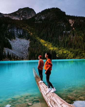 Couple standing on wood by lake against mountain