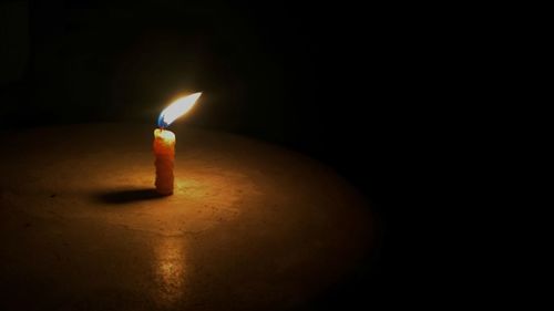 Close-up of lit candle in darkroom
