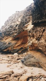 Rock formation at beach against sky