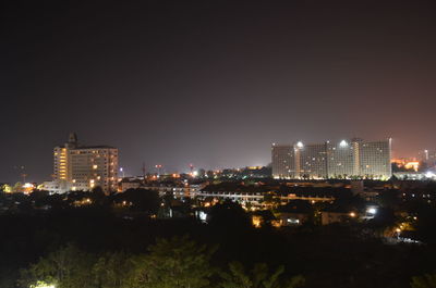 Illuminated buildings in city against sky at night