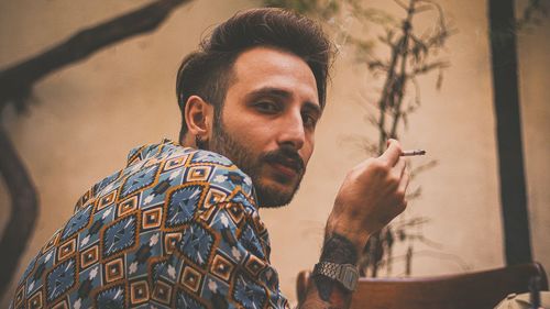 Portrait of young man smoking cigarette indoor