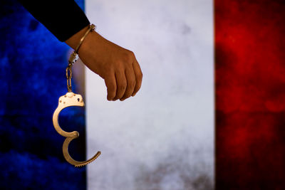 Cropped hand of male criminal with handcuffs against french flag