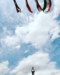 Low angle view of man and iranian flags against sky