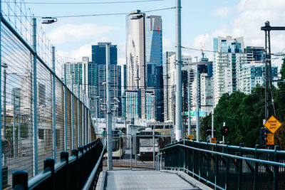 Footbridge amidst buildings in city against sky