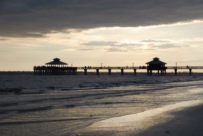 Pier on sea against cloudy sky